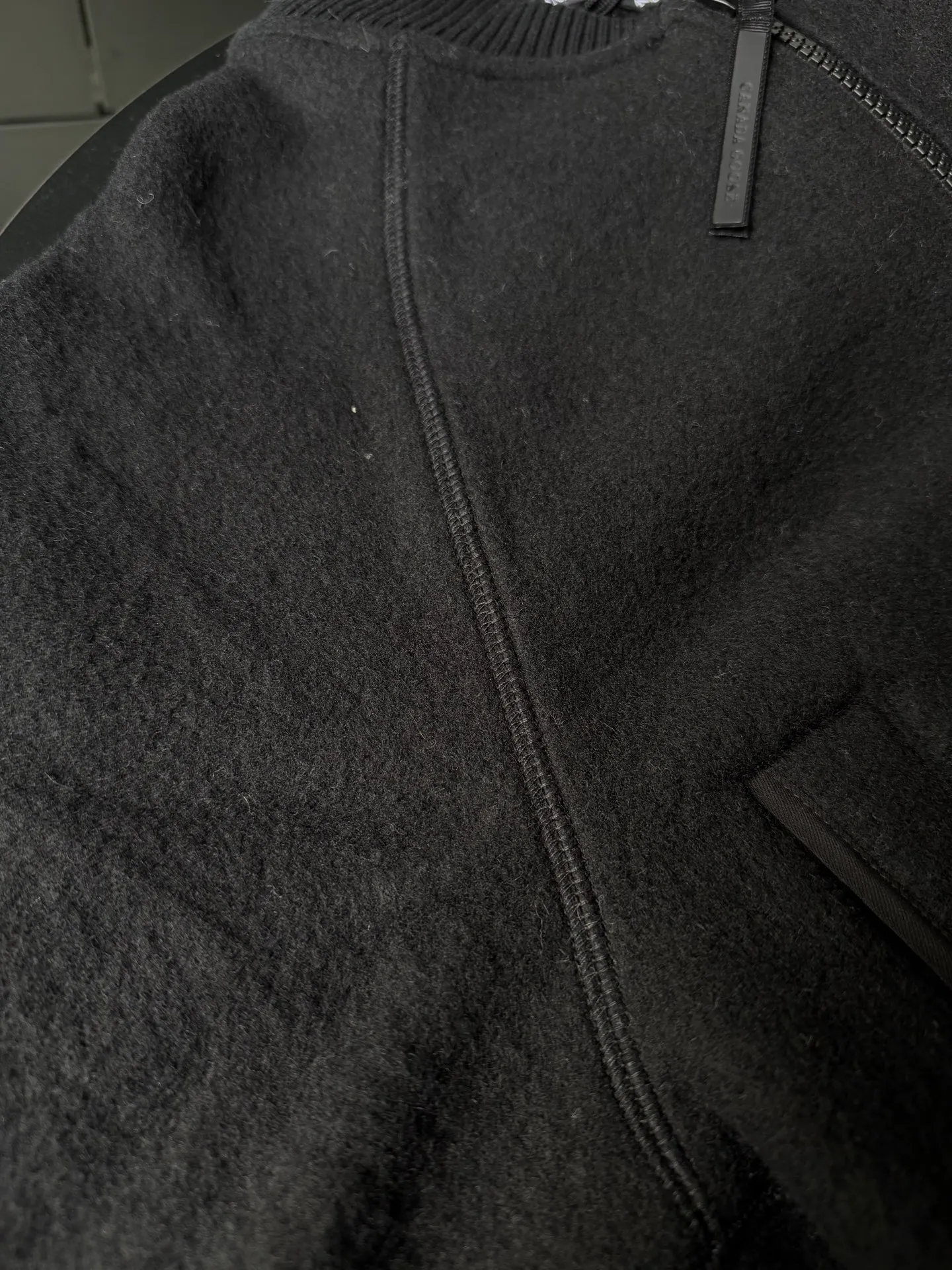 P620 Canada Goose Fleece Wool Baseball Jacket Fabric selection: Wool fleece fabric blended with wool as the main body and a very small amount of spandex and polyester fiber. Wool is a core natural ingredient that provides unparalleled temperature regulation, antibacterial and anti-odor properties and a skin-friendly feel. The feeding of a small amount of spandex gives the fabric a certain degree of four-way elasticity, making it non-restrictive during daily activities. As the basis of fleece's structure, polyester fiber enhances the fabric's durability, wrinkle resistance and quick-drying properties. It contributes to the loft of the fleece and provides functions such as trapping air.  Detail 1: The sleeves and hem are closed with 2×2 ribbing. Its strong elasticity can closely fit wrists and waists of different thicknesses, forming an effective 'seal' to prevent cold wind from blowing back. It can still maintain its original shape after repeated stretching and use, and is not easy to loose and deform. And the ribbed cuffs can convey a sense of design and enhance the visual beauty.  Detail 2: The combination of hood design and elastic buckle improves warmth and windproof performance when wearing. Accessories: Customized elastic drawstring, elastic buckle, custom zipper pendant, custom armband Size: S M L Color: Black Gray Mickey